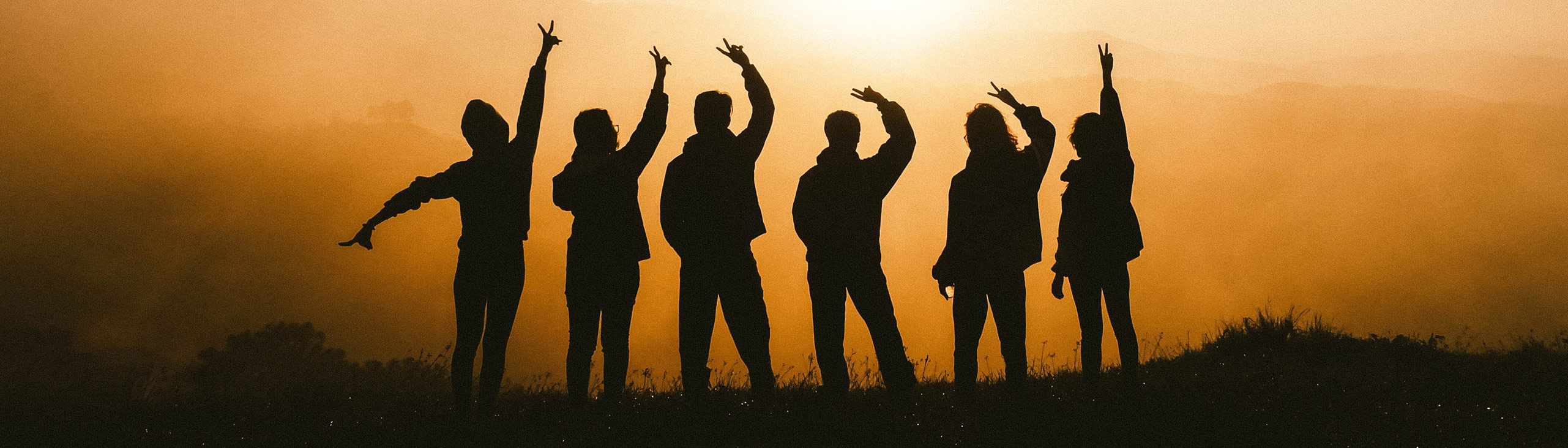 photo of 6 people in
      silhouette against a sunrise in the mountains