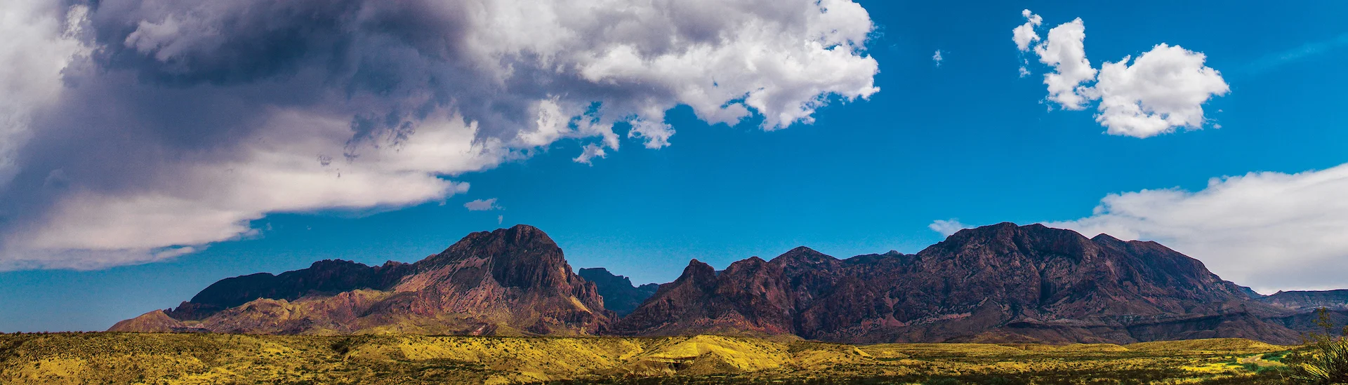 beautiful red mountains with green foliage foreground and blue sky background