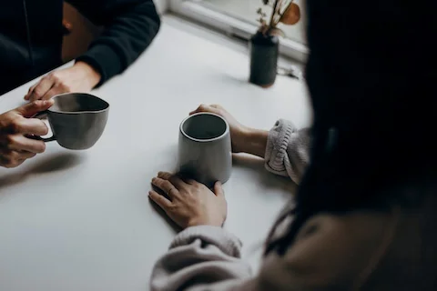 table with two people drinking coffee together