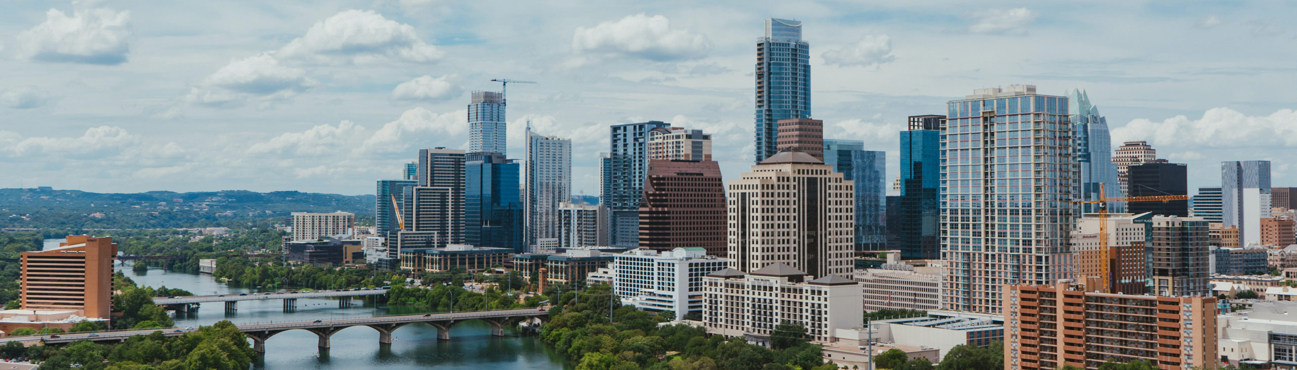 skyline of Austin, TX including skyscrapers, a river, and a bridge